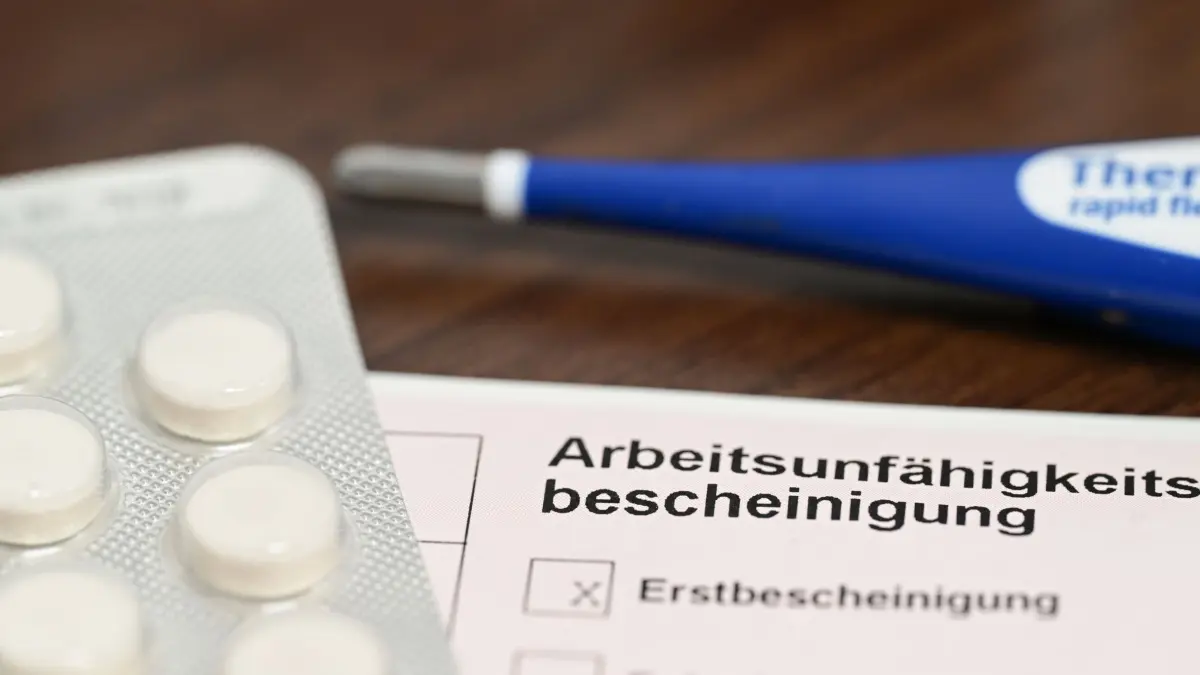 ARCHIV - 18.11.2022, Baden-Württemberg, Stuttgart: ILLUSTRATION - Ein Fieberthermometer, Medikamente und eine ärztliche Arbeitsunfähigkeitsbescheinigung (Krankmeldung) liegen auf einem Nachttisch (gestellte Szene). (zu dpa: «Krankenkassen: Krankschreibungen auch 2023 auf Rekordniveau») Foto: Bernd Weißbrod/dpa +++ dpa-Bildfunk +++