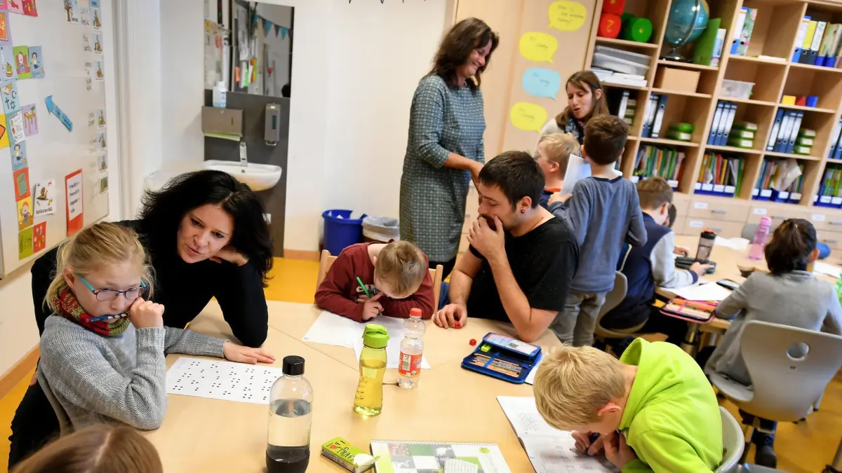 Die Schulassistenten Moni Floetenmeyer (Vordergrund l-r) und Philipp Schneider sowie die Sonderpädagogin Uschi Wessels (Hintergrund Mitte) beschäftigen sich mit Kindern während des Unterrichts am 02.11.2017 in der Otfried-Preussler-Schule in Hannover (Niedersachsen). An der Schule begleiten Schulassistenzen im Rahmen eines Pilotprojektes inklusive Klassen mit Kindern mit und ohne Behinderungen. (zu dpa «Experten warnen: Immer mehr Schulassistenten gefährden Inklusion» vom 05.11.2017) Foto: Holger Hollemann/dpa +++(c) dpa - Bildfunk+++