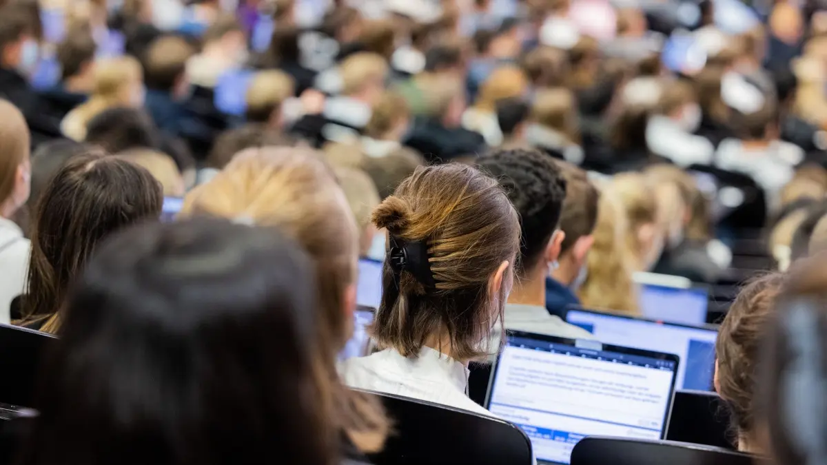 Studenten: ARCHIV - 11.10.2021, Nordrhein-Westfalen, Münster: Studentinnen und Studenten sitzen während einer Vorlesung in einem Hörsaal. Studentinnen und Studenten sowie Azubis haben einer neuen Yougov-Umfrage zufolge im Schnitt ein höheres Stressempfinden als Arbeitnehmer, die ihre Ausbildung hinter sich haben. (zu dpa: «Ministerium fördert psychologische Beratung von Studierenden») Foto: Rolf Vennenbernd/dpa +++ dpa-Bildfunk +++