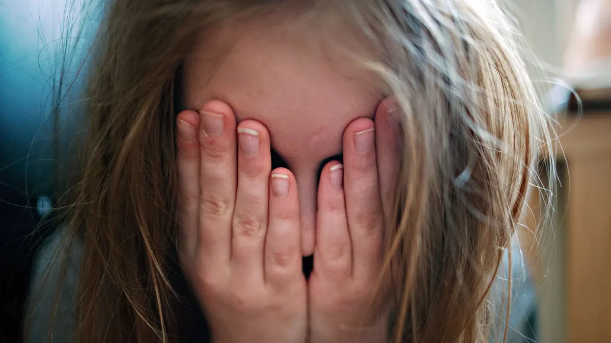 ILLUSTRATION - Ein junges Mädchen hält sich die Hände vor ihr Gesicht. Die Hinweise auf Kindeswohlgefährdung in Rheinland-Pfalz haben im vergangenen Jahr um 5,6 Prozent zugenommen. Üben deine Eltern viel Druck aus oder drohen mit Strafen, macht dich das bestimmt traurig. Dabei sollte man so eigentlich gar nicht miteinander reden. (zu dpa: «Auch Worte können verletzen»)