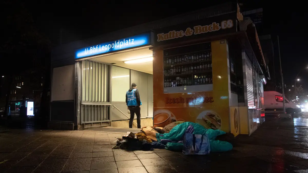 Ein Mitarbeiter des Kältebusses der Berliner Stadtmission steht am Bahnhof Leopoldplatz neben dem Lager eines Obdachlosen.
