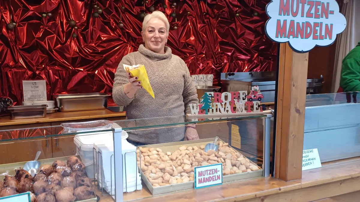 Angelique Schäfer verkauft auf dem Weihnachtsmarkt an der Berliner Gedächtskirche Mutzenmandeln, die ihr Schwiegervater schon auf DDR-Rummeln verkauft hat.