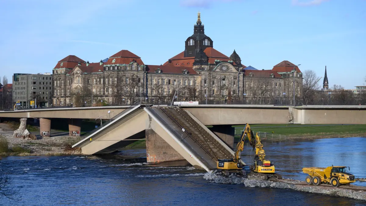 Carolabrücke in Dresden: ACHTUNG: SPERRFRIST 11. DEZEMBER 19:00 UHR. - ARCHIV - 05.12.2024, Sachsen, Dresden: Bagger sind auf der Altstädter Elbseite am eingestürzten Brückenzug der Carolabrücke auf einer Baustraße inmitten der Elbe mit dem Abriss der Brückenteile beschäftigt, im Hintergrund ist die Staatskanzlei zu sehen. Der westliche Brückenstrang mit Straßenbahngleisen, Rad- und Fußweg brach in der Nacht zum 11. September 2024 aus bisher unbekannten Gründen ein. (zu dpa: «Rest der Dresdner Carolabrücke nicht zu retten») Foto: Robert Michael/dpa +++ dpa-Bildfunk +++