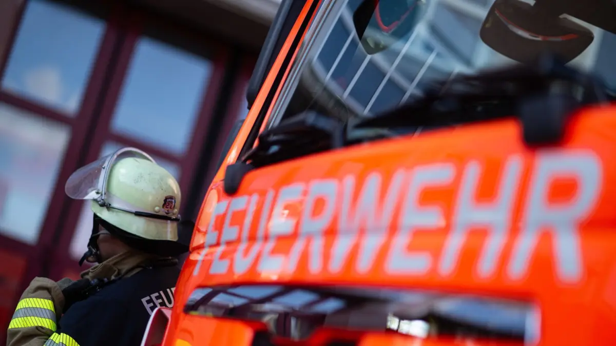ILLUSTRATION - 08.11.2023, Baden-Württemberg, Stuttgart: Eine Einsatzkraft der Feuerwehr steht neben einem Einsatzfahrzeug der Feuerwehr. (zu dpa: «Werkstatt mit zehn Autos ausgebrannt») Foto: Marijan Murat/dpa +++ dpa-Bildfunk +++