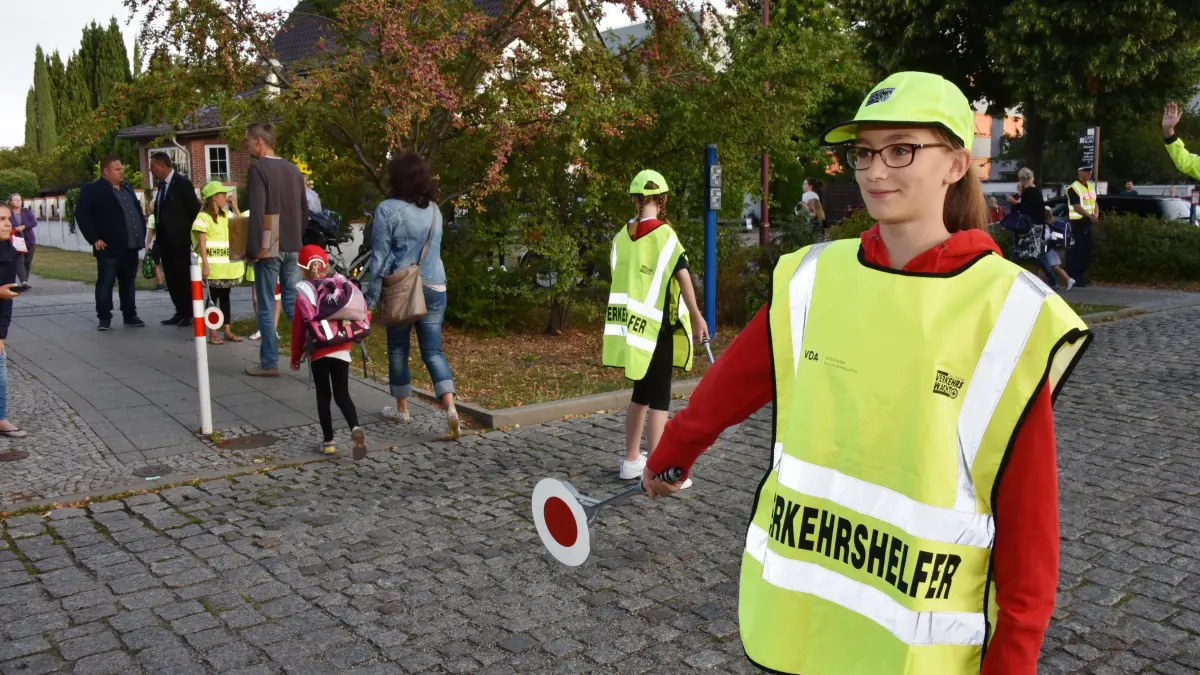 Schülerlotsen Drebkauer Strasse: Mit Warnweste und Lotsenkelle für einen sicheren Schulweg
Cottbus. Als am Montagmorgen die Erstklässler ihrer neuen Schule, der Sportbetonten Grundschule in der Drebkauer Straße, entgegeneilten, war auch die beste Schülerlotsin des Landes Brandenburg, Floriane Herfurth (rechts im Bild), dabei. Mit grüner Warnweste und Lotsenkelle sorgte die Siegerin des Landesausscheids „Bester Schülerlotse 2019“ gemeinsam mit ihren Mitschülerinnen, der Polizei und der Cottbuser Verkehrswacht dafür, dass die Mädchen und Jungen gefahrlos die Drebkauer Straße überqueren und ihre Schule sicher erreichen konnten. Floriane freute sich, dass sie den Landeswettbewerb gewonnen hat und nun im September am Bundeswettbewerb in Berlin teilnehmen wird. Zu ihrem Dienst als Schülerlotsin am ersten Schultag am Montag sagte sie: „Es ist wichtig, die Autofahrer gerade vor Schulen zu animieren, vorsichtig zu fahren und vor allem den Erstklässlern ein sicheres Gefühl beim Überqueren der Straßen zu geben“.
Zum Start des neuen Schuljahres wird die Polizei des Landes Brandenburg im Umfeld von Schulen wieder verstärkt auf die Sicherheit der Schülerinnen und Schüler achten. Dazu sind umfassende Kontrollen der Verkehrsteilnehmer geplant. Stellvertretend für alle anderen Schulstandorte im Land ist am Montagmorgen in der Drebkauer Straße in Cottbus die diesjährige Aktion „Sicherer Schulweg“ eröffnet worden. Die Siegerin des Landesausscheides „Bester Schülerlotse 2019“, Floriane Herfurth, hat mit ihren Mitschülerinnen und Mitschülern den Termin begleitet, und sie wirbt in den nächsten Wochen als Gesicht der Verkehrssicherheitskampagne auf Bannern in ganz Brandenburg für mehr Aufmerksamkeit im Straßenverkehr, insbesondere im Bereich von Grundschulen.
Der Leiter des Bereiches Verkehrsangelegenheiten im Polizeipräsidium Potsdam, Polizeioberrat Jan Strotzer, betonte, dass die Polizei in den nächsten 14 Tagen die Fahrweise der Verkehrsteilnehmer besonders vor Schulen