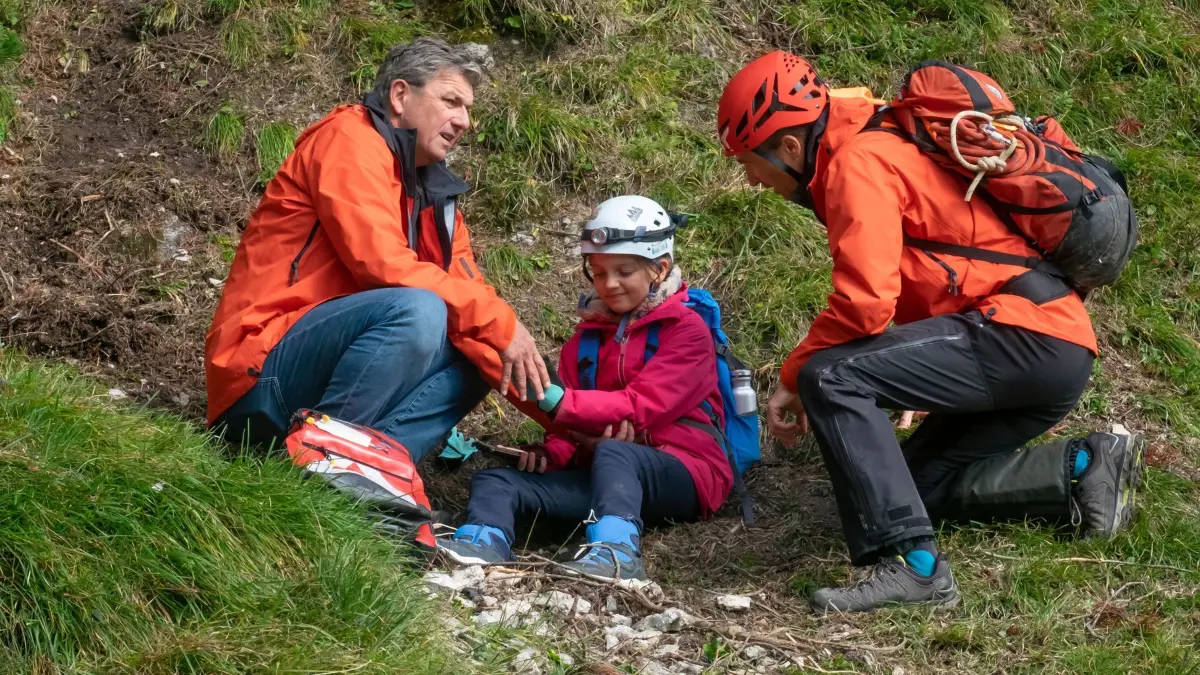 Die aufgeweckte Tamara Gotthart (Rosa Wirtz) ist den Berghang hinabgerutscht – Dr. Martin Gruber (Hans Sigl, l.) und Hans Gruber (Heiko Ruprecht, r.) kümmern sich um sie.