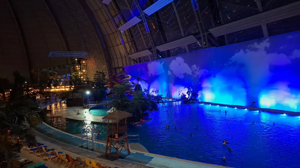 Der "Südsee"-Bereich in Tropical Islands ist am Abend in atmosphärisches Licht getaucht und gibt dem Wasser eine tiefblaue Farbe. Hingegen lässt die Beleuchtung des Lagunenpools das Wasser dort türkis erscheinen.