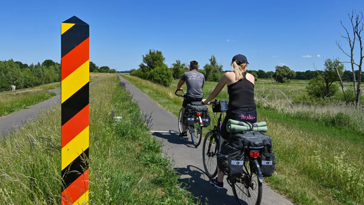 Fahrradfahrer sind auf dem Oder-Neiße-Radweg, der sich im Oderbruch auf dem Deich am deutsch-polnischen Grenzfluss Oder befindet, unterwegs. Der Oder-Neiße-Radweg ist ein rund 630 Kilometer langer Fernradweg in Tschechien und Deutschland. Er folgt weitgehend der deutschen Ostgrenze zu Polen. Der Oder-Neiße-Radweg verläuft in Süd-Nord-Richtung etwa 55 Kilometer durch Tschechien von der Quelle der Neiße ausgehend, dieser folgend bis zur Mündung der Neiße in die Oder. Westwärts der Oder führt dann der Weg entlang flacher Flusslandschaften zum Stettiner Haff und nach Ahlbeck auf Usedom.