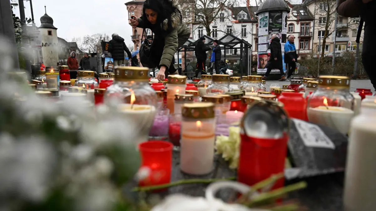 A woman lights a candle at a makeshift memorial for the victims of a knife attack, on January 23, 2025 in Aschaffenburg, western Germany. A knife attacker killed a two-year-old child and a man on January 22, 2025 in a public park in Aschaffenburg, where police arrested an Afghan man as the main suspect. (Photo by Kirill KUDRYAVTSEV / AFP)