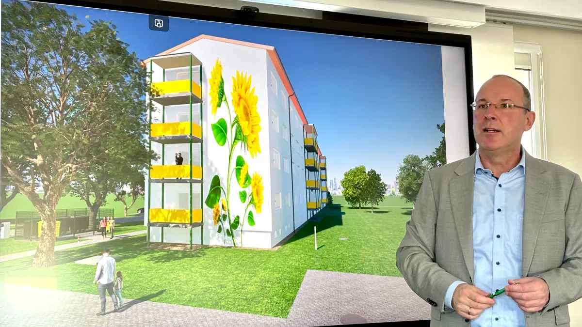 WH-Geschäftsführer Steffen Markgraf zeigt den Entwurf für das Wandbild, das künftig die Fassade des komplex sanierten Viergeschossers an der Johann-Gottfried-Herder-Straße 21-29 zieren soll.