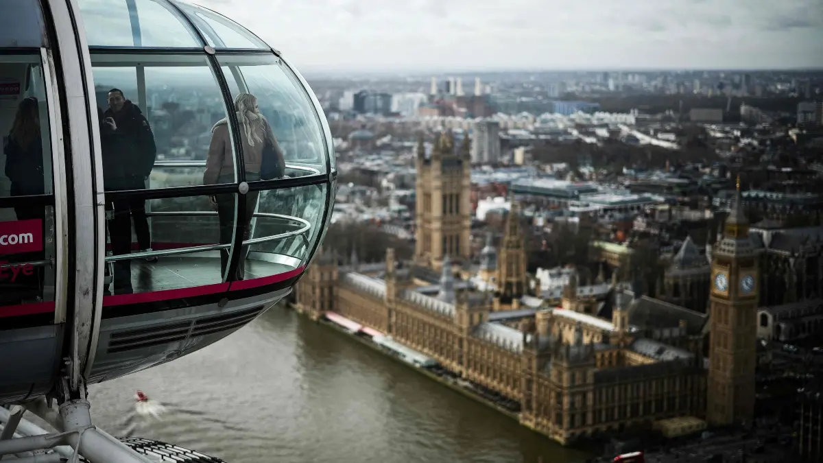 Embargoed until March 6, 2025 - 00:01 GMT / Visitors look out from a pod of the London Eye as they enjoy the view of the Elizabeth Tower, commonly known by the name of the clock's bell "Big Ben", and the Palace of Westminster, home to the Houses of Parliament, in central London, on February 25, 2025. Floating high above the London skyline aboard her most famous creation, architect Julia Barfield said she never expected the London Eye to take off as a design icon. The initial priority was finding a breathtaking way to see the city, she told AFP in an interview inside one of the giant ferris wheel's 32 glass pods, now drifting against the backdrop of the Houses of Parliament. (Photo by HENRY NICHOLLS / AFP)