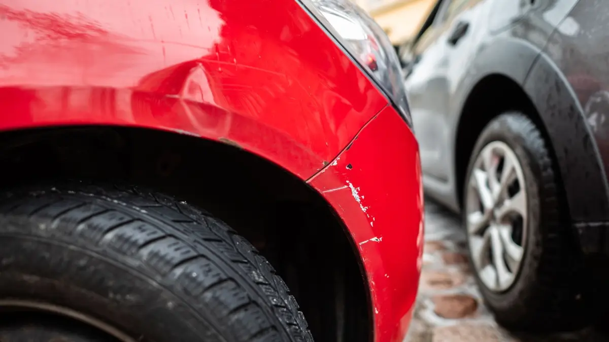 Unfallschaden: ARCHIV - 22.01.2024, Sachsen, Dresden: Ein rotes Autos steht mit einem Blechschaden in einer Parklücke, während ein graues Auto vorbei fährt. (zu dpa: «Senior misslingt das Ausparken in Dresden - hoher Schaden») Foto: Robert Michael/dpa +++ dpa-Bildfunk +++