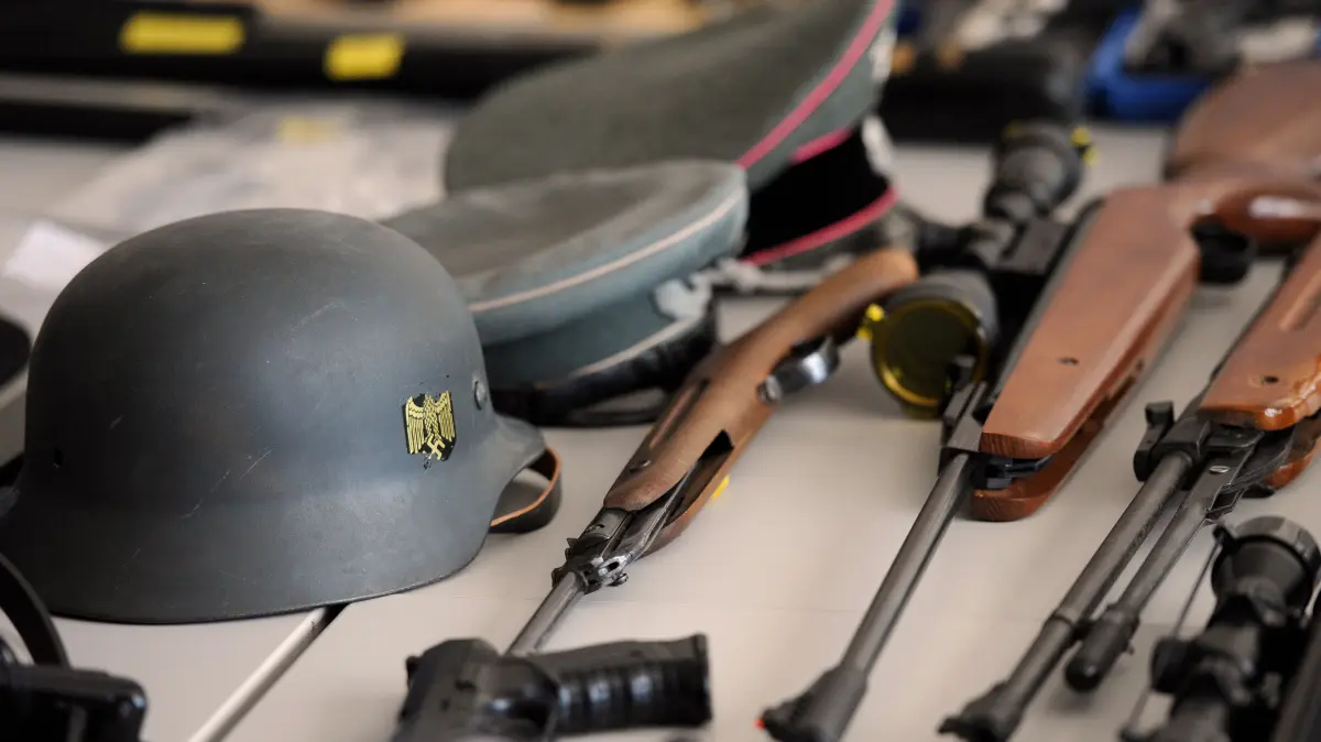 ARCHIV - Beschlagnahmte Waffen und Gegenstände liegen am Donnerstag (23.08.2012) bei einer Pressekonferenz zum Verbot von rechtsextremistischer Vereinigungen in Stolberg bei Aachen auf dem Tisch. In Nordrhein-Westfalen dürfen fast 100 Rechtsextremisten legal eine Waffe besitzen. Die Behörden prüften derzeit in jedem Einzelfall, ob die Waffenerlaubnis nach geltendem Recht wieder entzogen werden könne, teilte das Düsseldorfer Innenministerium am Dienstag mit. «Wir wollen keine Waffen in den Händen von Neonazis», erklärte Innenminister Jäger (SPD). Wer sich aktiv gegen die Verfassung stelle, dürfe keine Schusswaffe legal besitzen. Foto: Henning Kaiser dpa/lnw +++ dpa-Bildfunk +++