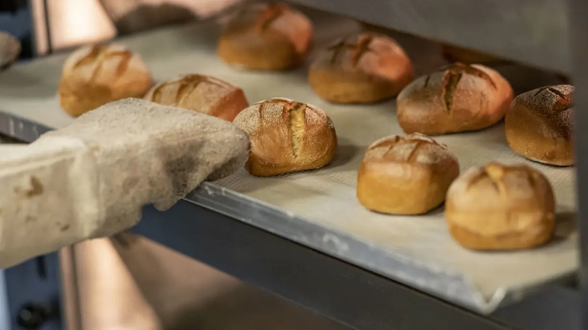 ARCHIV - 08.09.2022, Berlin: Eine Person schiebt in der Bäcker-Innung Berlin ein Blech mit Brötchen in einen Ofen. (zu dpa: «Bäckerinnen und Bäcker bekommen zum ersten März 5,9 Prozent mehr Lohn») Foto: Fabian Sommer/dpa +++ dpa-Bildfunk +++