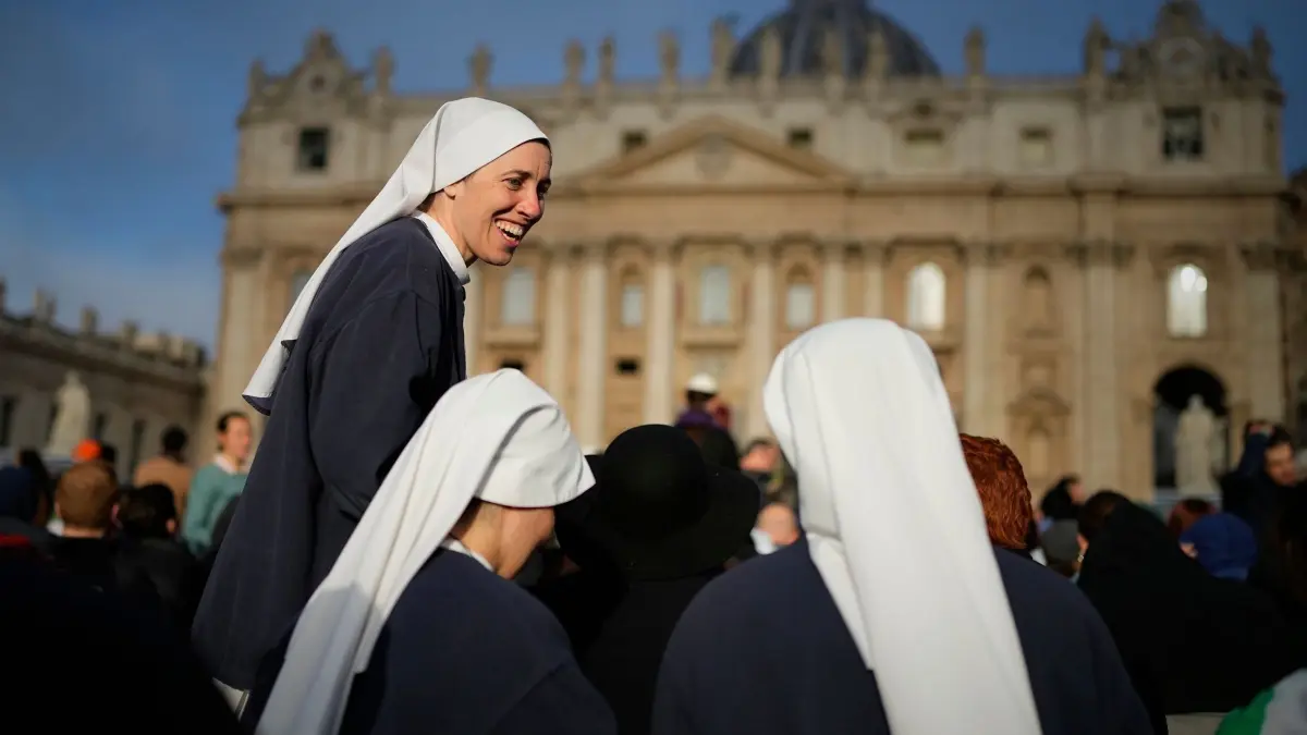 Papst Franziskus gestorben - Beisetzung: 26.04.2025, Vatikan, Vatikanstadt: Nonnen lachen gemeinsam, während sich die Menschen zur Beerdigung von Papst Franziskus auf dem Petersplatz im Vatikan versammeln. Foto: Andreea Alexandru/AP/dpa +++ dpa-Bildfunk +++