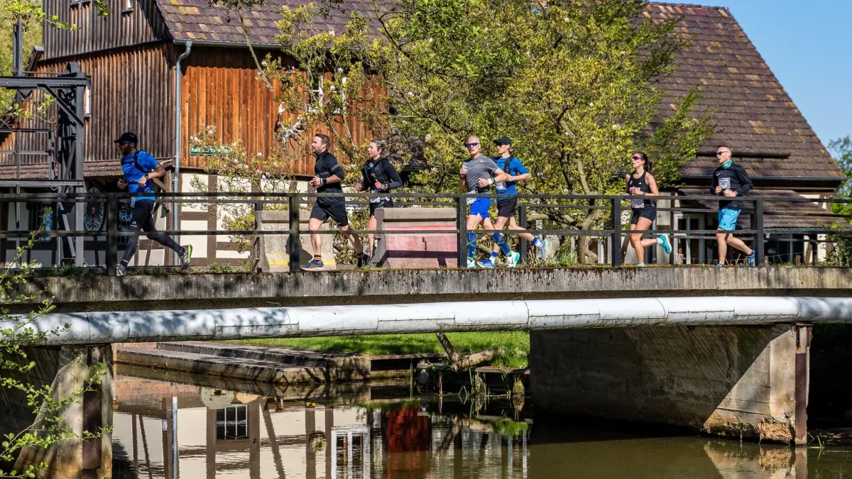 Spreewald-Marathon: 27.04.2025, Brandenburg, Straupitz: Sportlerinnen und Sportler laufen beim Spreewaldmarathon über eine Brücke, die über ein Fließ (eine Wasserstraße im Spreewald) führt. Das größte Freizeitsport-Ereignis in der Region findet in diesem Jahr bereits zum 23. Mal statt. Foto: Frank Hammerschmidt/dpa +++ dpa-Bildfunk +++