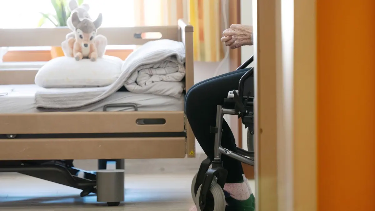 Pflegeheim: ARCHIV - 03.04.2025, Sachsen, Dresden: Ein Bewohner sitzt in einem Altenheim in seinem Zimmer in einem Rollstuhl. Auf dem gemachten Bett liegt ein Stofftier. (zu dpa: «DGB Sachsen verlangt Kurswechsel in der Pflegepolitik») Foto: Sebastian Kahnert/dpa +++ dpa-Bildfunk +++