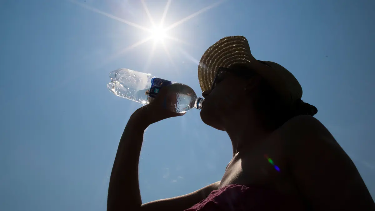 ILLUSTRATION - Eine Frau mit Sonnenhut trinkt am 03.07.2015 in Recklinghausen (Nordrhein-Westfalen) unter der Mittagssonne aus einer Wasserflasche. Gerade bei hohen Temperaturen ist ausreichend Flüssigkeit im Körper wichtig. Foto: Marcel Kusch/dpa ++ +++ dpa-Bildfunk +++