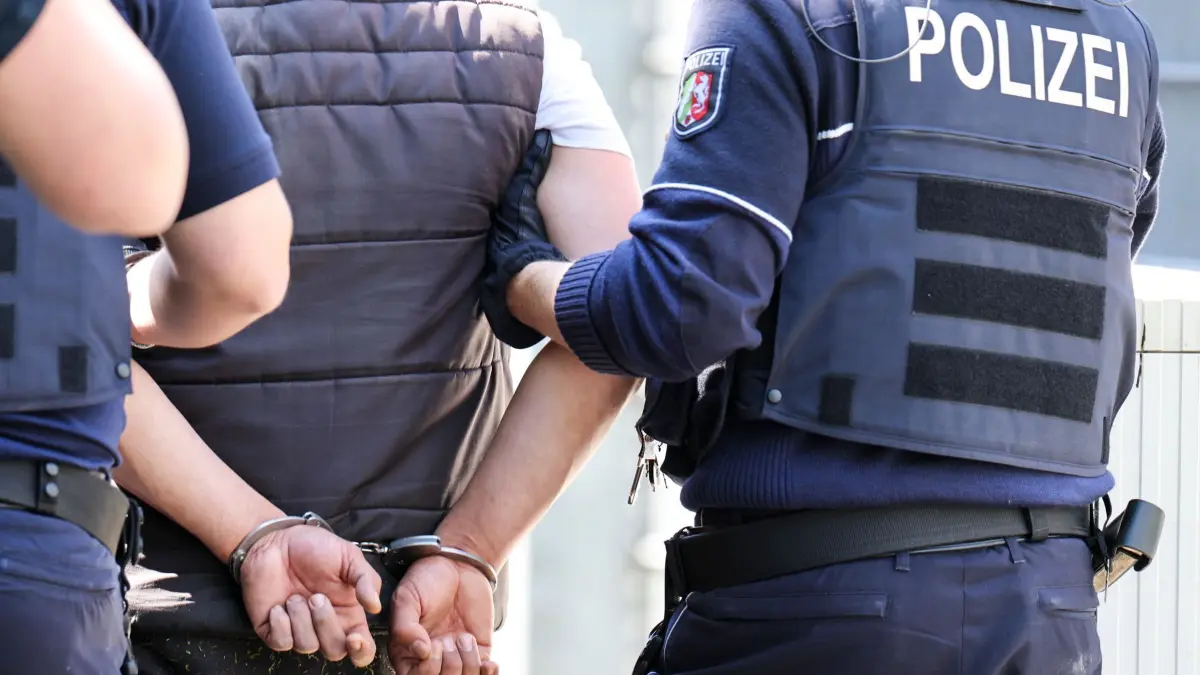 SEK-Großeinsatz in NRW-Forensik: 10.05.2025, Nordrhein-Westfalen, Bedburg-Hau: Polizeibeamte führen eine Person nach Randale in einer psychiatrischen Klinik in Handschellen ab. Mit einem Großeinsatz von Polizeikräften und Spezialeinheiten hat die Polizei eine Randale in der forensischen LVR-Klinik in Bedburg-Hau am Niederrhein aufgelöst. Foto: Christoph Reichwein/dpa +++ dpa-Bildfunk +++