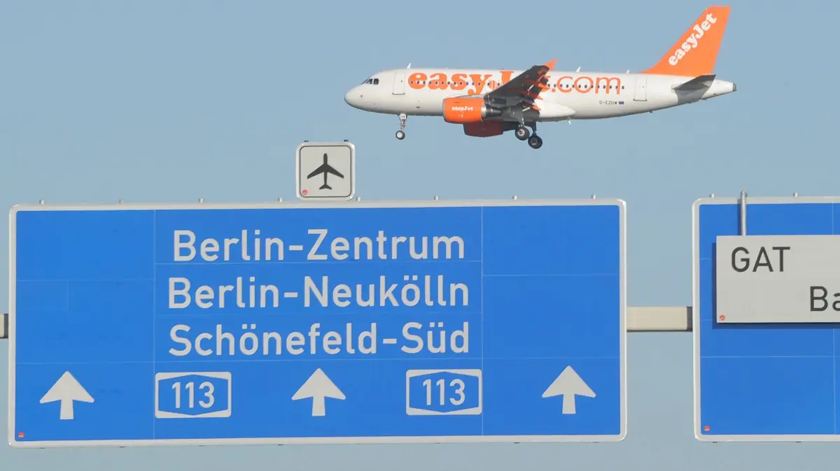 Ein Flugzeug fliegt am Donnerstag (13.10.2011) in Schönefeld über die A113, wo die Zufahrt zur Baustelle des BER Airport ausgeschildert ist. Das Verwaltungsgericht in Leipzig wies am selben Tag die Klage von Anwohnern für ein erweitertes Nachtflugverbot am künftigen Hauptstadtflughafen BER ab. Wenn der Flugbetrieb am neuen Willy Brandt Airport am 3. Juni 2012 offiziell startet, sollen rund 27 Millionen Passagiere in Berlin jährlich abgefertigt werden. Foto: Bernd Settnik dpa/lbn ++ +++ dpa-Bildfunk +++