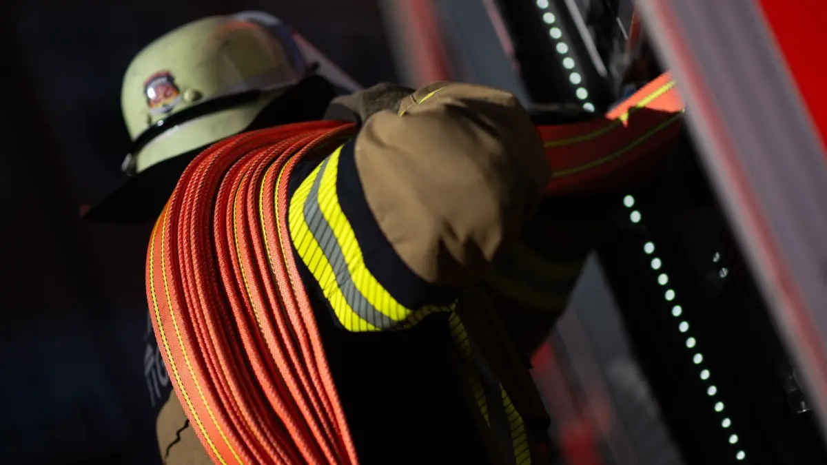 Feuerwehr - Symbolbild: ILLUSTRATION - 08.11.2023, Baden-Württemberg, Stuttgart: Eine Einsatzkraft der Feuerwehr nimmt einen Schlauch aus einem Einsatzfahrzeug der Feuerwehr Stuttgart. (zu dpa: «Kulissen in Flammen - Lagerhalle brennt») Foto: Marijan Murat/dpa +++ dpa-Bildfunk +++
