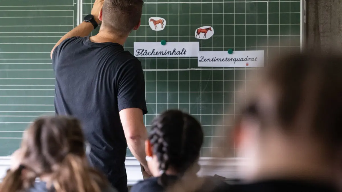 ARCHIV - 27.06.2024, Baden-Württemberg, Neckartailfingen: Ein Lehrer macht im Unterricht einer vierten Klasse einer Grundschule einen Tafelanschrieb, während an der Tafel Zettel mit der Aufschrift «Flächeninhalt» und «Zentimeterquadrat» hängen. (zu dpa: «Umfrage unter Schulleitern: Gewalt an Schulen hat zugenommen») Foto: Marijan Murat/dpa +++ dpa-Bildfunk +++