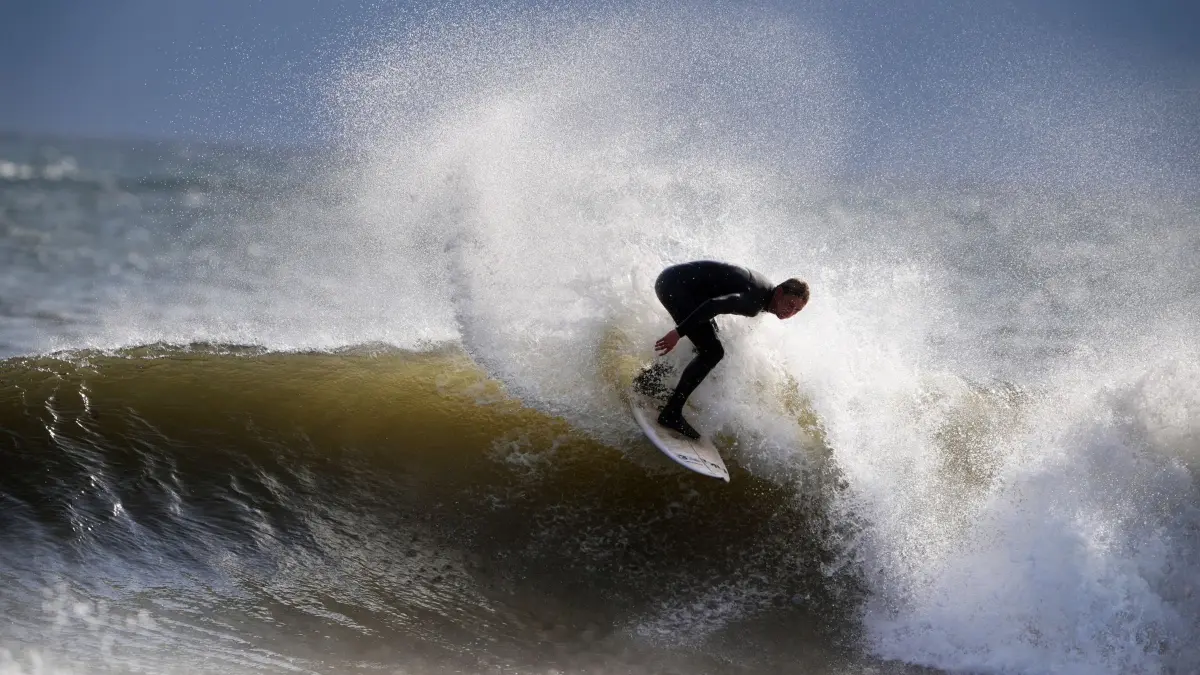 Surfen am englischen Nordseestrand: 31.07.2025, Großbritannien, Tynemouth: Ein Surfer am Strand von Tynemouth Longsands an der englischen Nordostküste. Foto: Owen Humphreys/PA Wire/dpa +++ dpa-Bildfunk +++