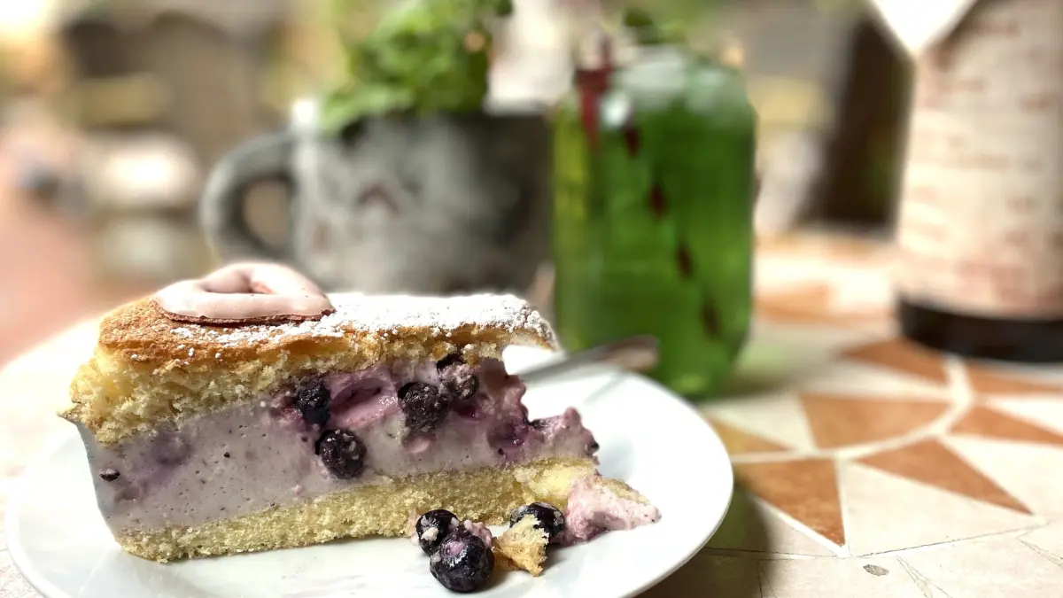 Heidelbeer-Joghurt-Torte im Hofcafé in Lübbenau am 01.08.2025, im Hintergrund Minz-Apfel-Schorle