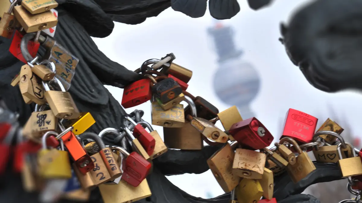 Verliebte hängen als Zeichen der Verbundenheit Schlösser an Brückengeländer in Berlin.