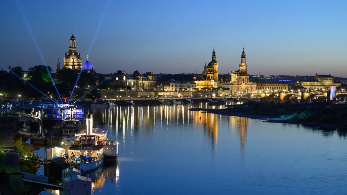 Dresden am Abend: 19.08.2025, Sachsen, Dresden: Lichter einer Party auf einem Schiff der Sächsischen Dampfschifffahrt Weiße Flotte sind am Abend vor der historischen Altstadtkulisse an der Elbe mit der Frauenkirche (l-r), der Kuppel der Kunstakedmie mit dem Engel „Fama“, dem Terrassenufer, dem Ständehaus, dem Hausmannsturm, der Hofkirche und der Semperoper zu sehen. Nach dem Abriss der Carolabrücke sind neue Sichtachsen auf die Altstadt entstanden. Foto: Robert Michael/dpa +++ dpa-Bildfunk +++
