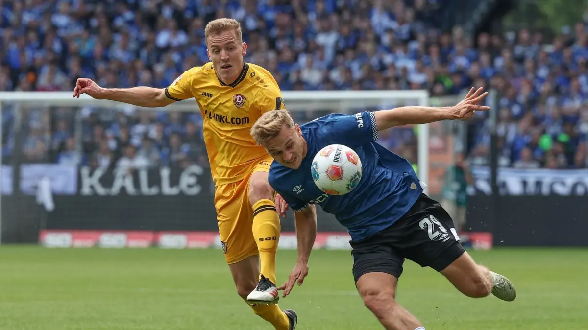 Arminia Bielefeld - Dynamo Dresden: 24.08.2025, Nordrhein-Westfalen, Bielefeld: Fußball: 2. Bundesliga, Arminia Bielefeld - Dynamo Dresden, 3. Spieltag, SchücoArena. Tim Handwerker (r, Arminia Bielefeld) und Niklas Hauptmann (Dynamo Dresden) im Kampf um den Ball. Foto: Friso Gentsch/dpa - WICHTIGER HINWEIS: Gemäß den Vorgaben der DFL Deutsche Fußball Liga bzw. des DFB Deutscher Fußball-Bund ist es untersagt, in dem Stadion und/oder vom Spiel angefertigte Fotoaufnahmen in Form von Sequenzbildern und/oder videoähnlichen Fotostrecken zu verwerten bzw. verwerten zu lassen. +++ dpa-Bildfunk +++