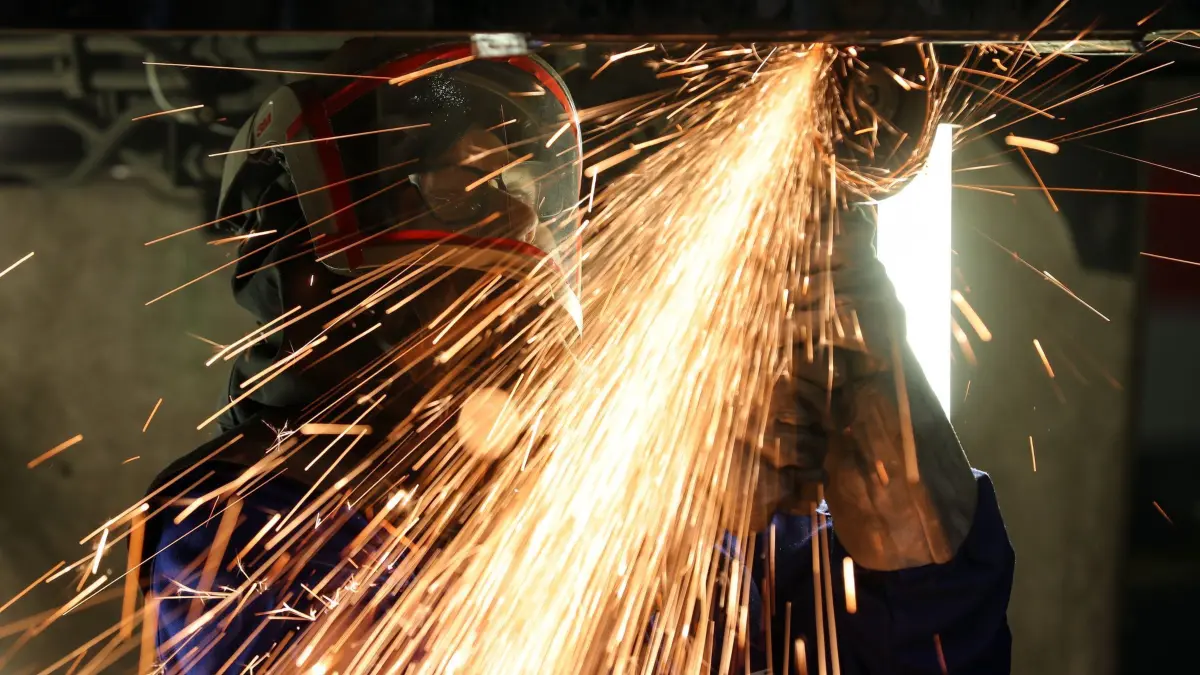 Maschinenbauer: ARCHIV - 22.01.2020, Sachsen-Anhalt, Halle: Ein Mitarbeiter eines Maschinenbauers schneidet mit einem Trennschleifer korrodierte Metallteile aus dem Träger in einem Wagenkasten. Die Branche musste 2024 einen realen Auftragsrückgang von 22 Prozent hinnehmen – besonders das Jahresende brachte tiefe Einschnitte. (zu dpa: «Ifo Institut: Geschäftsklima im Osten hellt sich leicht auf») Foto: Jan Woitas/dpa-Zentralbild/dpa +++ dpa-Bildfunk +++