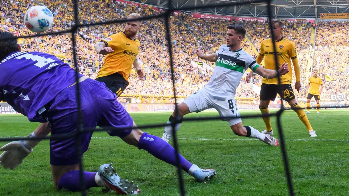 SG Dynamo Dresden - Hannover 96: 21.09.2025, Sachsen, Dresden: Fußball: 2. Bundesliga, Dynamo Dresden - Hannover 96, 6. Spieltag, Rudolf-Harbig-Stadion, Nils Fröling (Dynamo Dresden, 2.v.l) erzielt gegen Torwart Nahuel Noll (Hannover 96) und Enzo Leopold (Hannover 96) das Tor zum 2:1. Foto: Robert Michael/dpa - WICHTIGER HINWEIS: Gemäß den Vorgaben der DFL Deutsche Fußball Liga bzw. des DFB Deutscher Fußball-Bund ist es untersagt, in dem Stadion und/oder vom Spiel angefertigte Fotoaufnahmen in Form von Sequenzbildern und/oder videoähnlichen Fotostrecken zu verwerten bzw. verwerten zu lassen. +++ dpa-Bildfunk +++