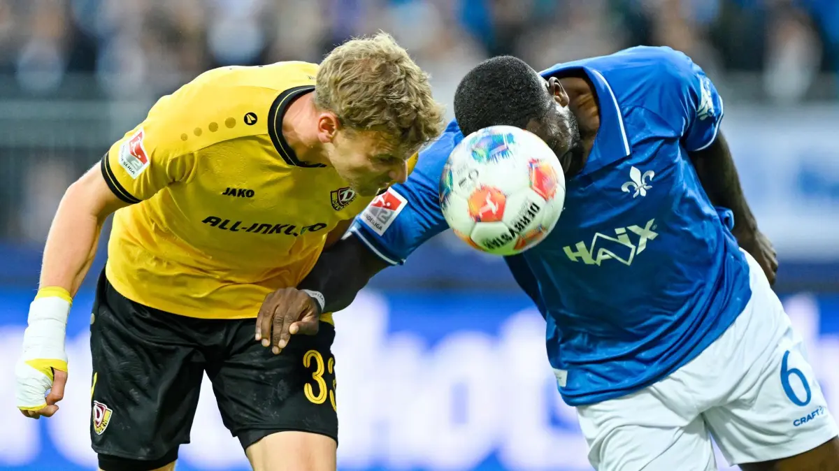 Darmstadt 98 - Dynamo Dresden: 26.09.2025, Hessen, Darmstadt: Fußball: 2. Bundesliga, Darmstadt 98 - Dynamo Dresden, 7. Spieltag, Merck-Stadion am Böllenfalltor. Christoph Daferner (l, Dynamo Dresden) und Patric Pfeiffer (SV Darmstadt 98) kämpfen um den Ball. Foto: Uwe Anspach/dpa - WICHTIGER HINWEIS: Gemäß den Vorgaben der DFL Deutsche Fußball Liga bzw. des DFB Deutscher Fußball-Bund ist es untersagt, in dem Stadion und/oder vom Spiel angefertigte Fotoaufnahmen in Form von Sequenzbildern und/oder videoähnlichen Fotostrecken zu verwerten bzw. verwerten zu lassen. +++ dpa-Bildfunk +++
