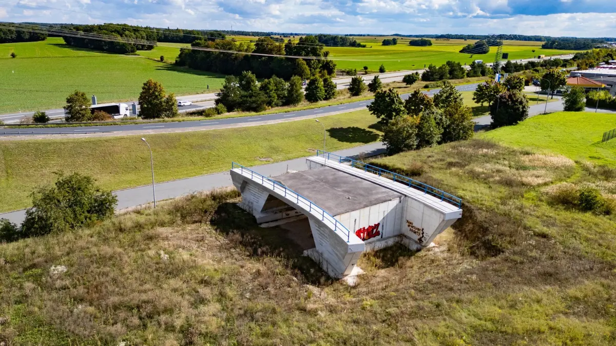 Brückenbauwerk auf Wiese: 29.09.2025, Sachsen, Radeburg: Eine Brücke für die geplante Straße S177 nahe der Autobahn A13 steht in einem Gewerbegebiet auf einer Wiese. (Aufnahme mit Drohne) (zu dpa: «Brücke ins Nichts und Fahrradbarometer landen im Schwarzbuch») Foto: Robert Michael/dpa +++ dpa-Bildfunk +++