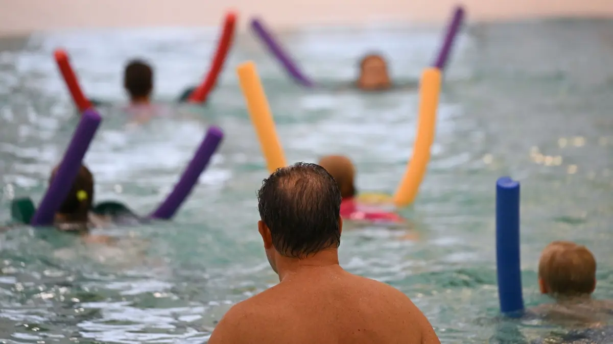 Schwimmunterricht: ARCHIV - 14.08.2024, Hessen, Frankfurt/Main: Schwimmlehrer Achim Heftrich (vorn) von der Schwimmschule Frankfurt leitet einen Schwimmkurs. (zu dpa: «Knapp die Hälfte der Viertklässler in MV schwimmt sicher») Foto: Arne Dedert/dpa +++ dpa-Bildfunk +++