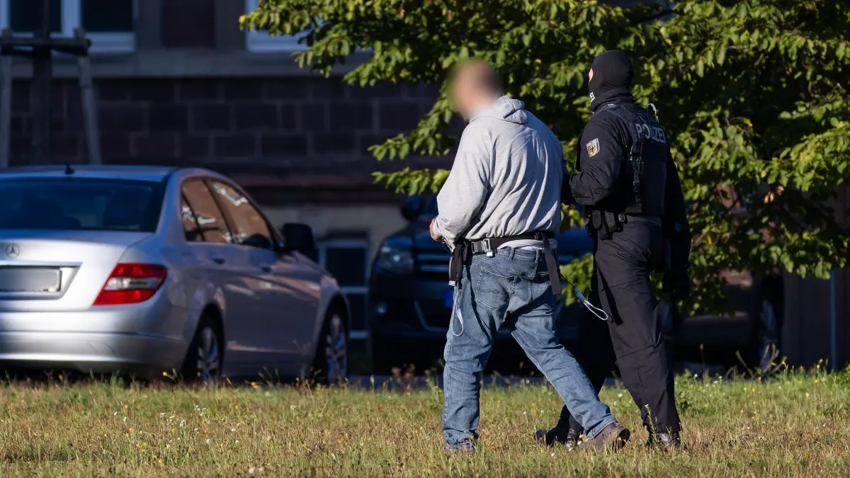 Waffenfund nach Festnahmen in Berlin: ARCHIV - 02.10.2025, Baden-Württemberg, Karlsruhe: Ein mutmaßliches Mitglied der islamistischen Terrororganisation Hamas wird von einem Bundespolizisten von einem Helikopter (nicht im Bild) zu einem Fahrzeug der Bundespolizei geführt. (zu dpa: «Nach Hamas-Festnahmen in Berlin: Waffenfund in Österreich») Foto: Philipp von Ditfurth/dpa - ACHTUNG: Person aus rechtlichen Gründen gepixelt +++ dpa-Bildfunk +++