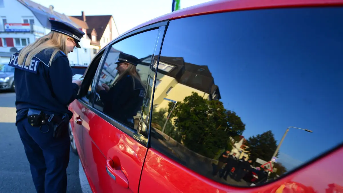 Eine Polizistin sichtet Dokumente bei einer Verkehrskontrolle: ARCHIV - Bei der Kontrolle den Fahrzeugschein digital auf dem Smartphone zeigen: Das geht nun mit der i-Kfz-App. (zu dpa: «Wie kommt der digitale Fahrzeugschein in die App?») Foto: Martin Schutt/dpa - Honorarfrei nur für Bezieher des Dienstes dpa-Magazin +++ dpa-Magazin +++