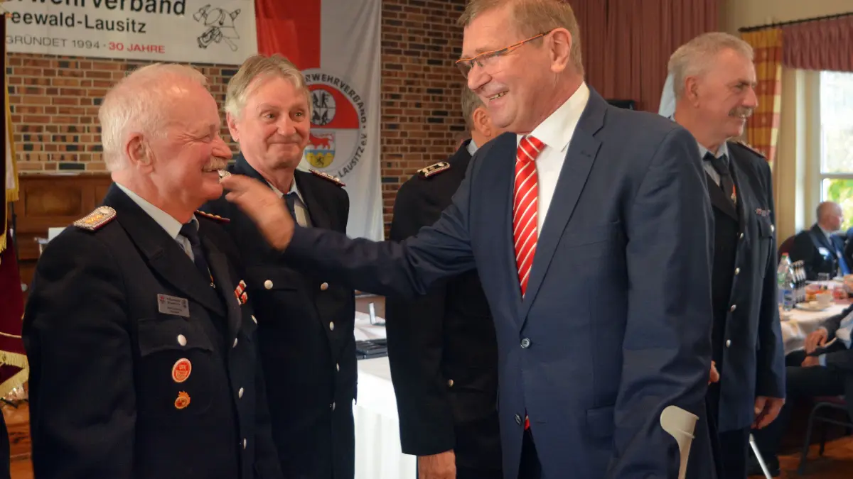 Manfred Mrose (l.) konnte die Medaille für 50 Jahre treue Dienste in den Reihen der Freiwilligen Feuerwehr in Empfang nehmen. Zu den ersten Gratulanten zählte Landrat Siegurd Heinze (parteilos), der den Jubilar anerkennend auf die Schulter klopfte. Von 1994 bis 2018 war Manfred Mrose Vorsitzender des KFV-OSL und ist jetzt Ehrenvorsitzender.
