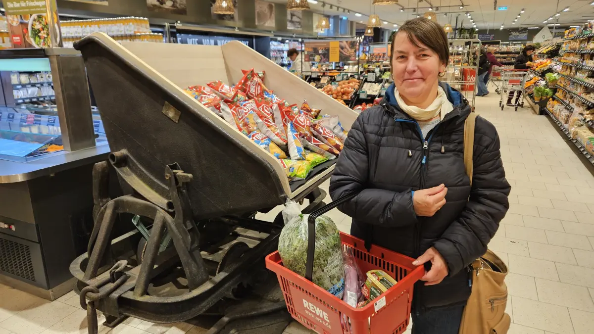 Ein Stück Heimat kehrt zurück: Petra Tkocz, ehemalige Rewe-Mitarbeiterin, stöbert spontan durch den wiedereröffneten Rewe-Markt und steht vor der historischen Lore aus Hosena, die jetzt als Regal dient.