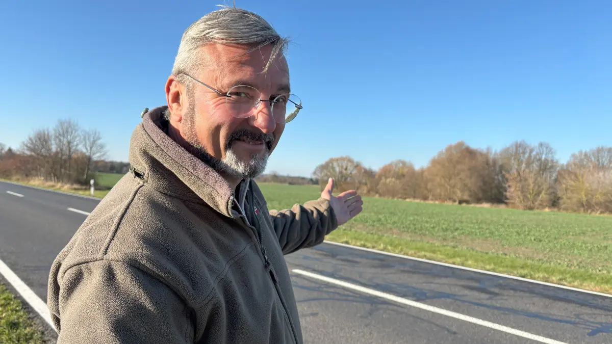 Torsten Große, Vorsitzender des Jagdverbandes Luckau, an der B87 vor Langengrassau. Er zeigt auf den Borchelt Langengrassau. Dort verweilen Rehe, weil sie geschützt sind, treten heraus, äsen und queren für neue Futterplätze hier oft die Straße.