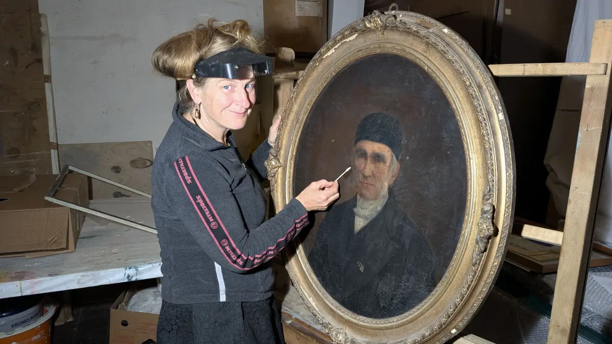 Dorothee Schmidt-Breitung säubert das zeitgenössische Gemälde mit Johann August Schneller, Ehrenbürger von Guben. Der Künstler ist unbekannt.