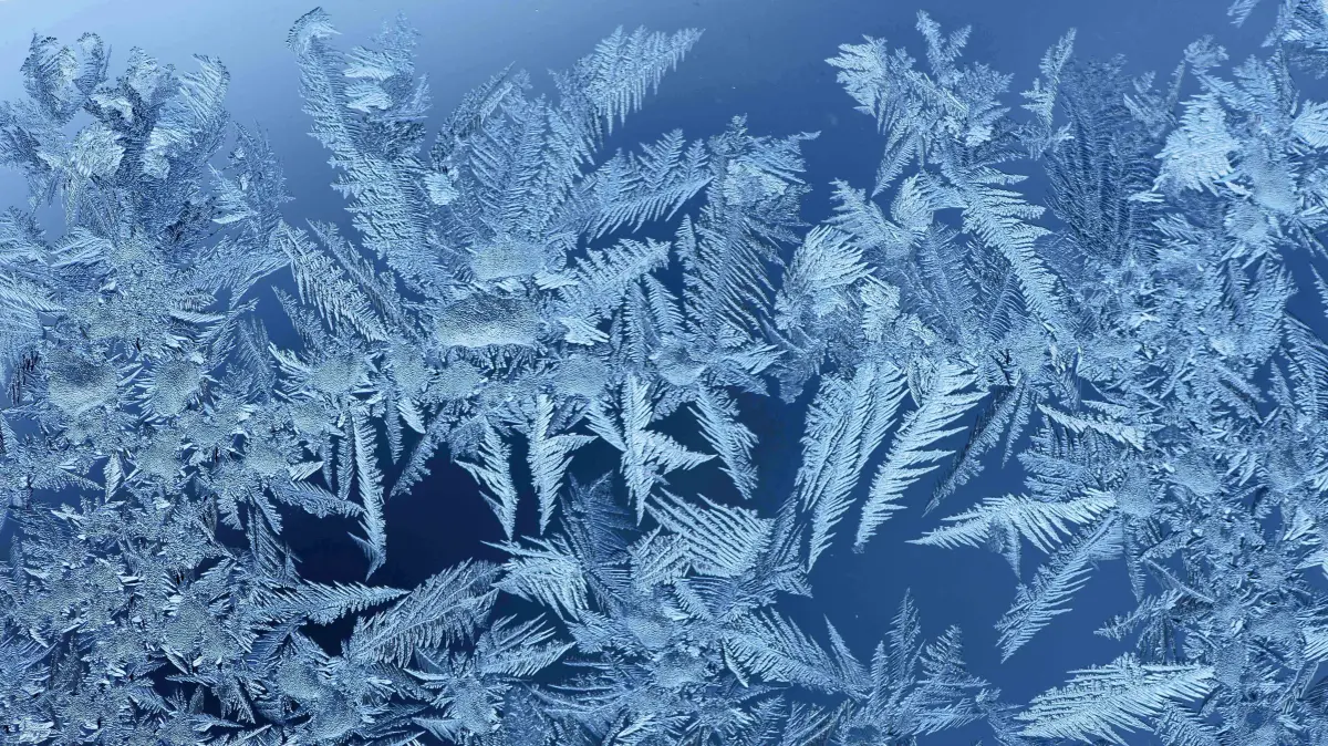 Eisblumen sind nach einer eisig kalten Nacht an einem Fenster zu sehen.