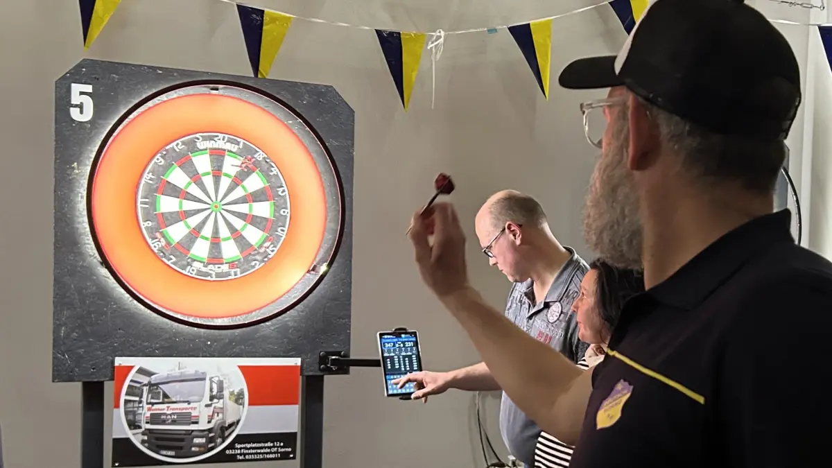 Darts wird in Elbe-Elster immer beliebter. Silvio Hübler aus Sorno, hier beim Wurf, hat Dartboard-Ständer angefertigt, die im ganzen Landkreis zum Einsatz kommen. Auch beim letzten Turnier nahe Finsterwalde war der Saal wieder voll.
