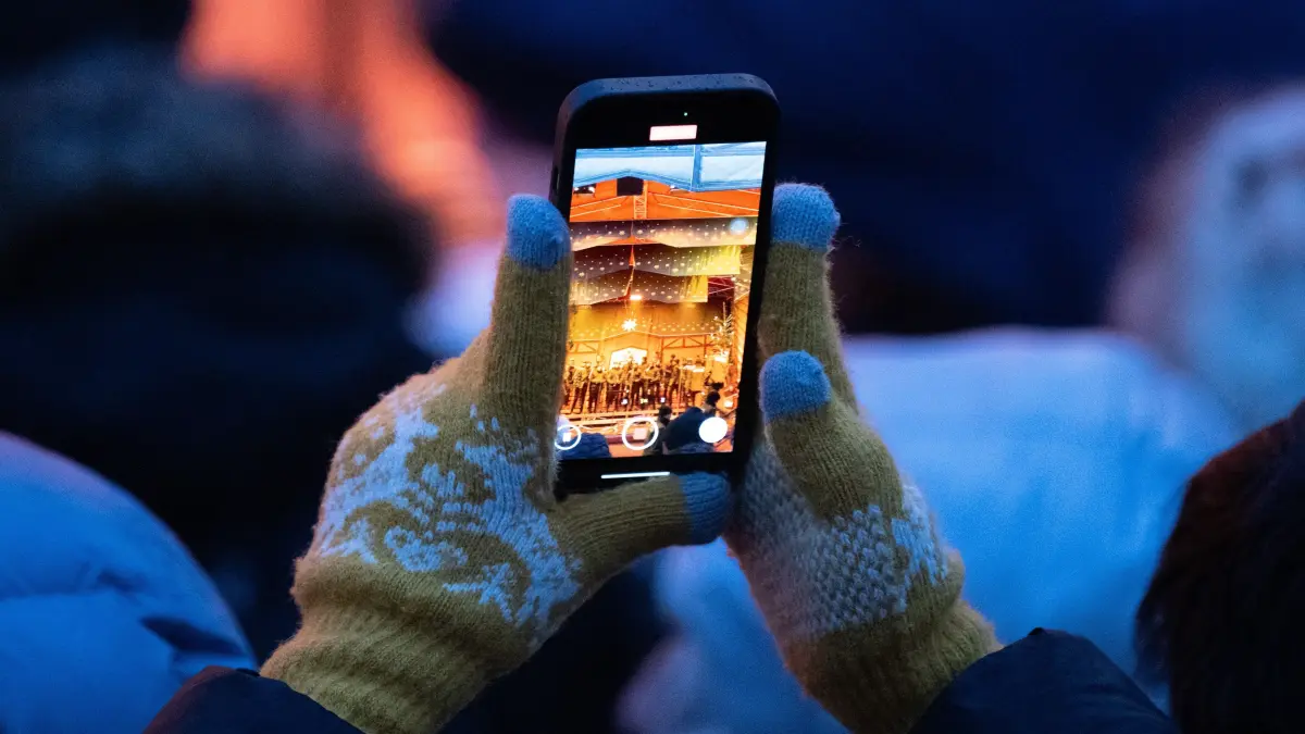 Eine Frau filmt die Eröffnungszeremonie eines beliebten Weihnachtsmarkts in Sachsen mit einem Smartphone.