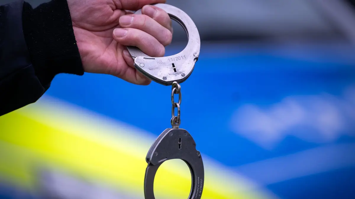 Handschellen Symbolbild: ARCHIV - 22.03.2024, Brandenburg, Trebbin: Ein Polizist hält ein Paar Handschellen. (zu dpa: «Polizei nimmt Mann nach Waffenfund fest») Foto: Soeren Stache/dpa +++ dpa-Bildfunk +++
