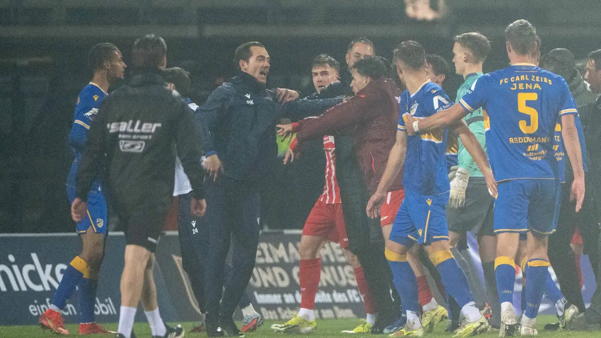 RLNO RW Erfurt - FC Carl Zeiss Jena 2025/26: Fußball, Herren, Saison 2025/2026, Regionalliga Nordost (17. Spieltag), FC Rot-Weiß Erfurt - FC Carl Zeiss Jena (3:1), Romarjo Hajrulla (mit weinroter Jacke/Erfurt) stößt nach Abpfiff Co- und Torwarttrainer Paul Küas (3. v. l., FC Carl Zeiss Jena) um und sieht dafür kurz darauf die Rote Karte, 28.11.2025, Foto: Matthias Koch