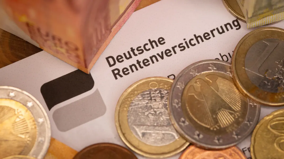 Ein Schreiben der Deutschen Rentenversicherung liegt zwischen Euro-Banknoten und mehreren Euromünzen. Bundeskanzler Merz hat im Bundestag erneut schnelle Sozialreformen in Aussicht gestellt und mit Blick auf die Rente für einen «neuen Konsens der Generationen» geworben. +++ dpa-Bildfunk +++