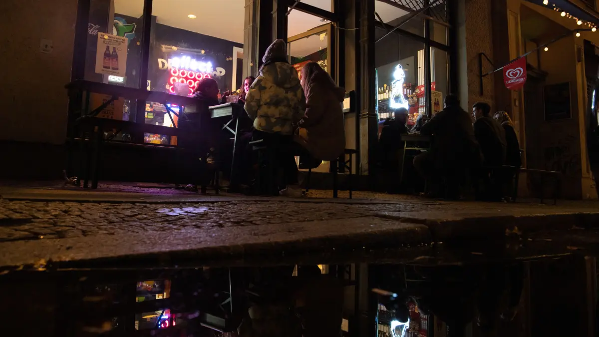 Menschen sitzen vor Beginn der Sperrstunde vor einem Spätkauf an der Oranienstraße. Die meisten Geschäfte sowie alle Restaurants und Bars müssen von 23.00 Uhr bis 06.00 Uhr schließen. +++ dpa-Bildfunk +++