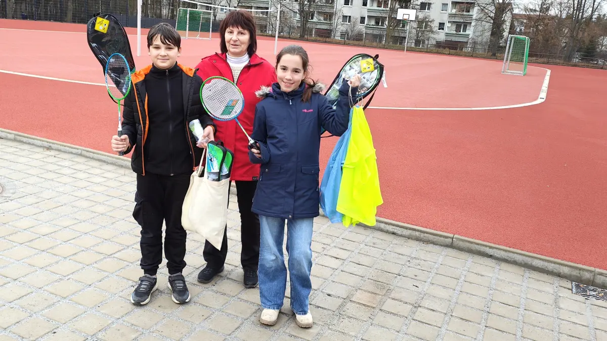 Paula und Roman freuen sich mit Schulleiterin Ines Förster über das abgeschlossene Projekt an der Grundschule Lauta und die von der Stadt bereitgestellten Federballspiele.